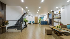 A spacious living area with a staircase, a dining table, and a sofa. - Lena Homestay (Da Nang)