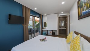 A hotel room with a large bed, a flat-screen TV mounted on the wall, a small kitchenette, and a sliding glass door leading to an outdoor area. - Lena Homestay (Da Nang)
