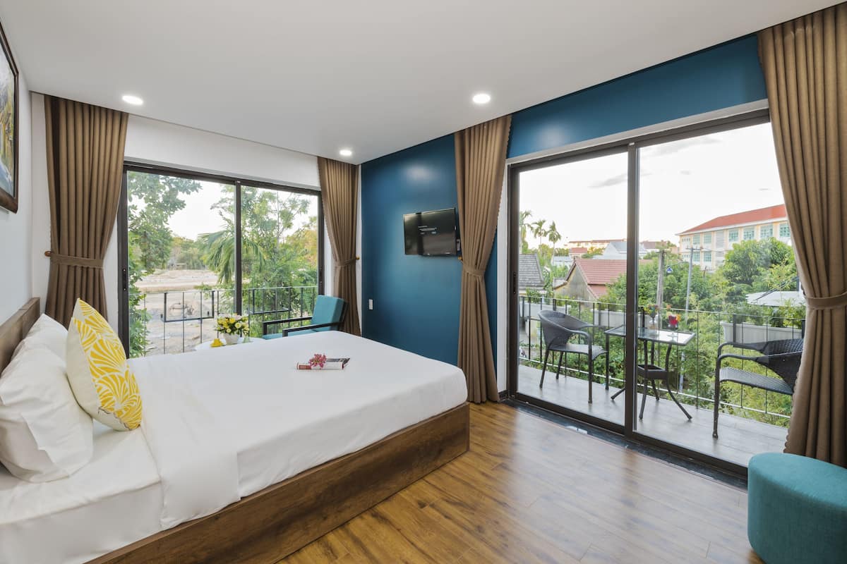 A bedroom with a bed, a TV, and a balcony with outdoor furniture.