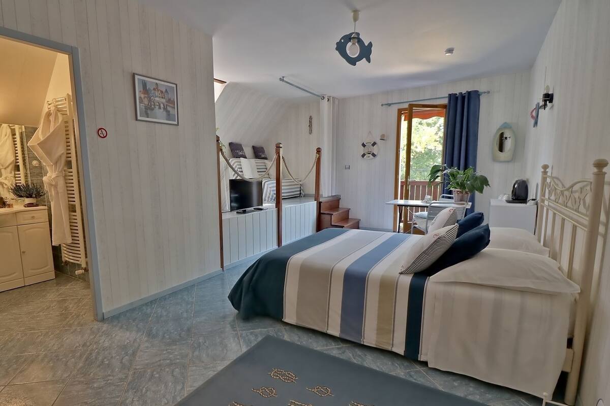 Un dormitorio con cama, escritorio, silla y ventana con cortinas.