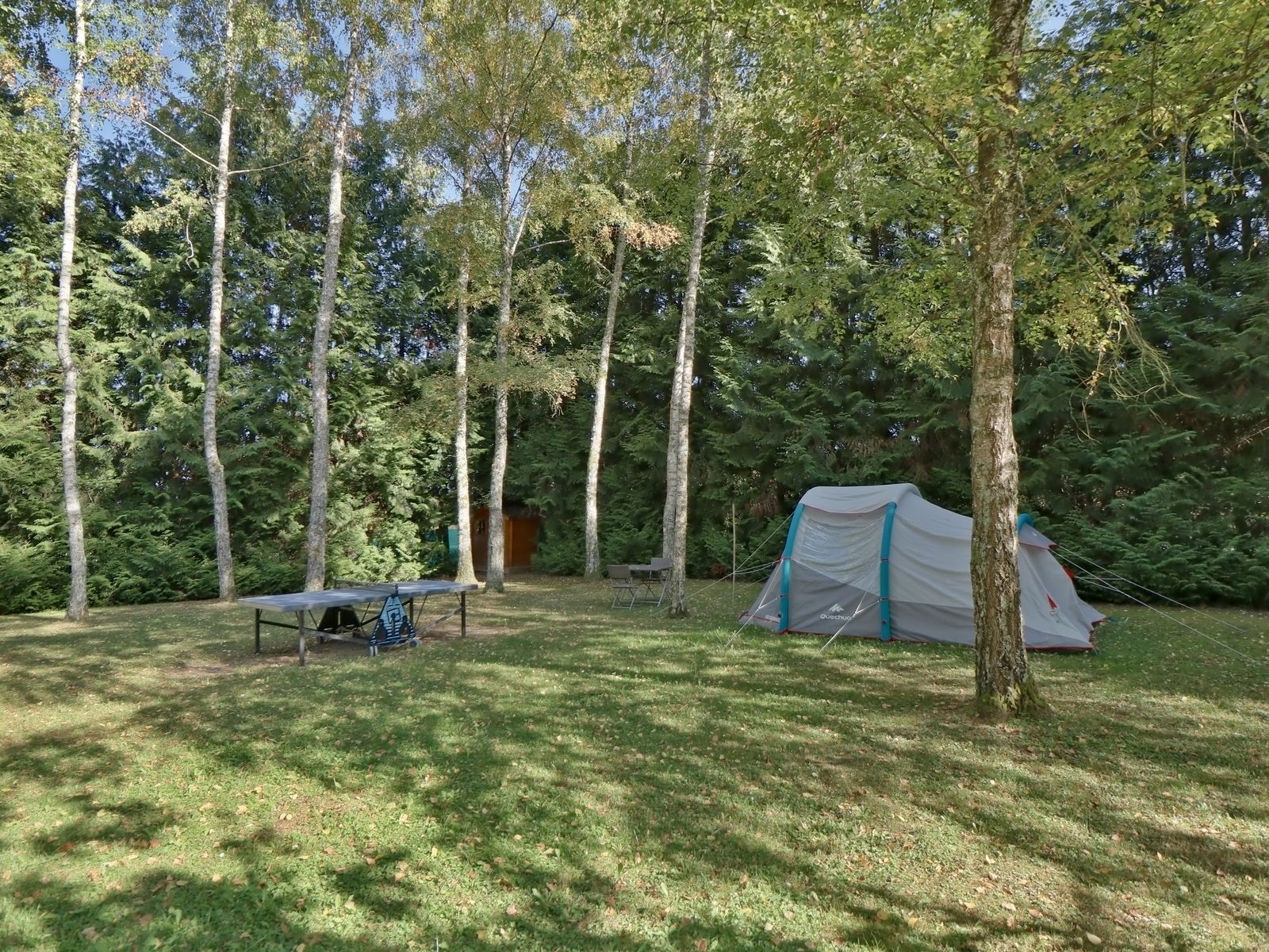 A camping area with a tent, a table, and a bench.