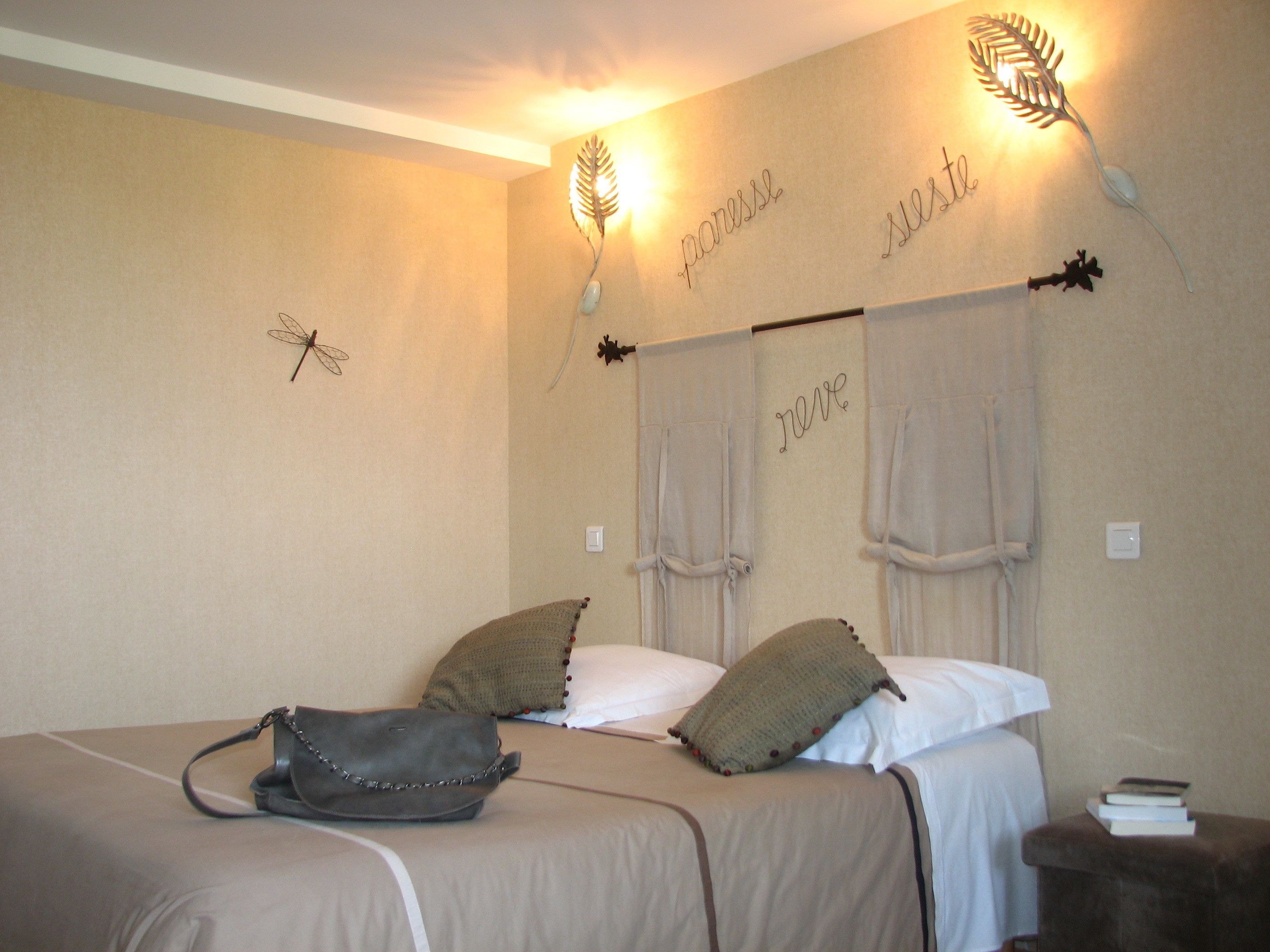 A bedroom with a bed, pillows, a handbag, and decorative wall art.