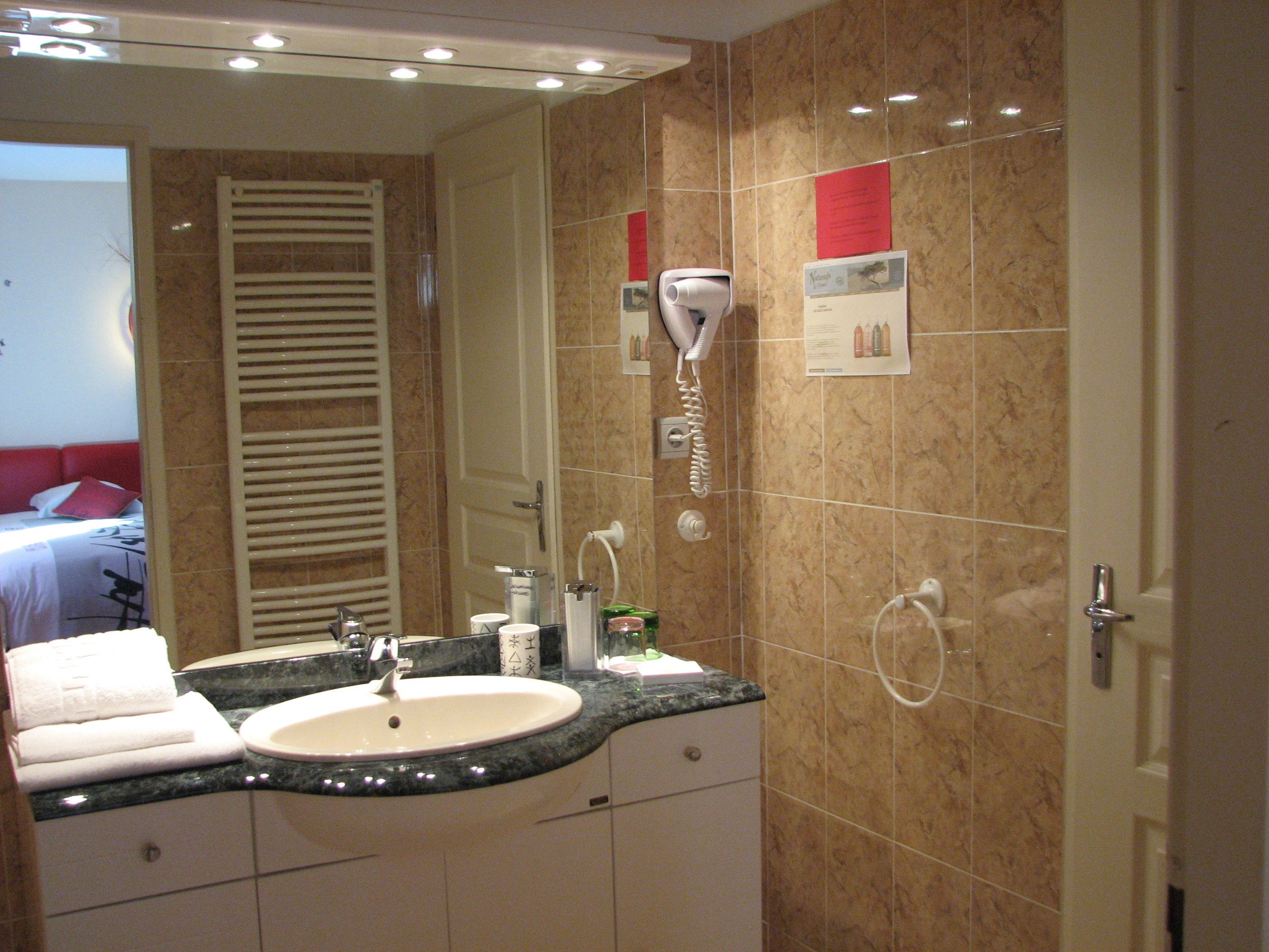 A bathroom with a sink, mirror, towel rack, and a hairdryer on the wall.