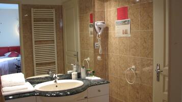 A bathroom with a sink, mirror, towel rack, and a hairdryer on the wall.