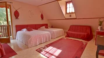 Un dormitorio con dos camas, un sofá rojo, un tapete rojo y una mesita con una planta.