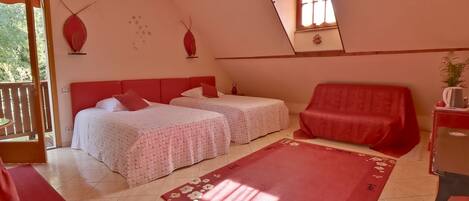 Un dormitorio con dos camas, un sofá rojo, un tapete rojo y una mesita con una planta.