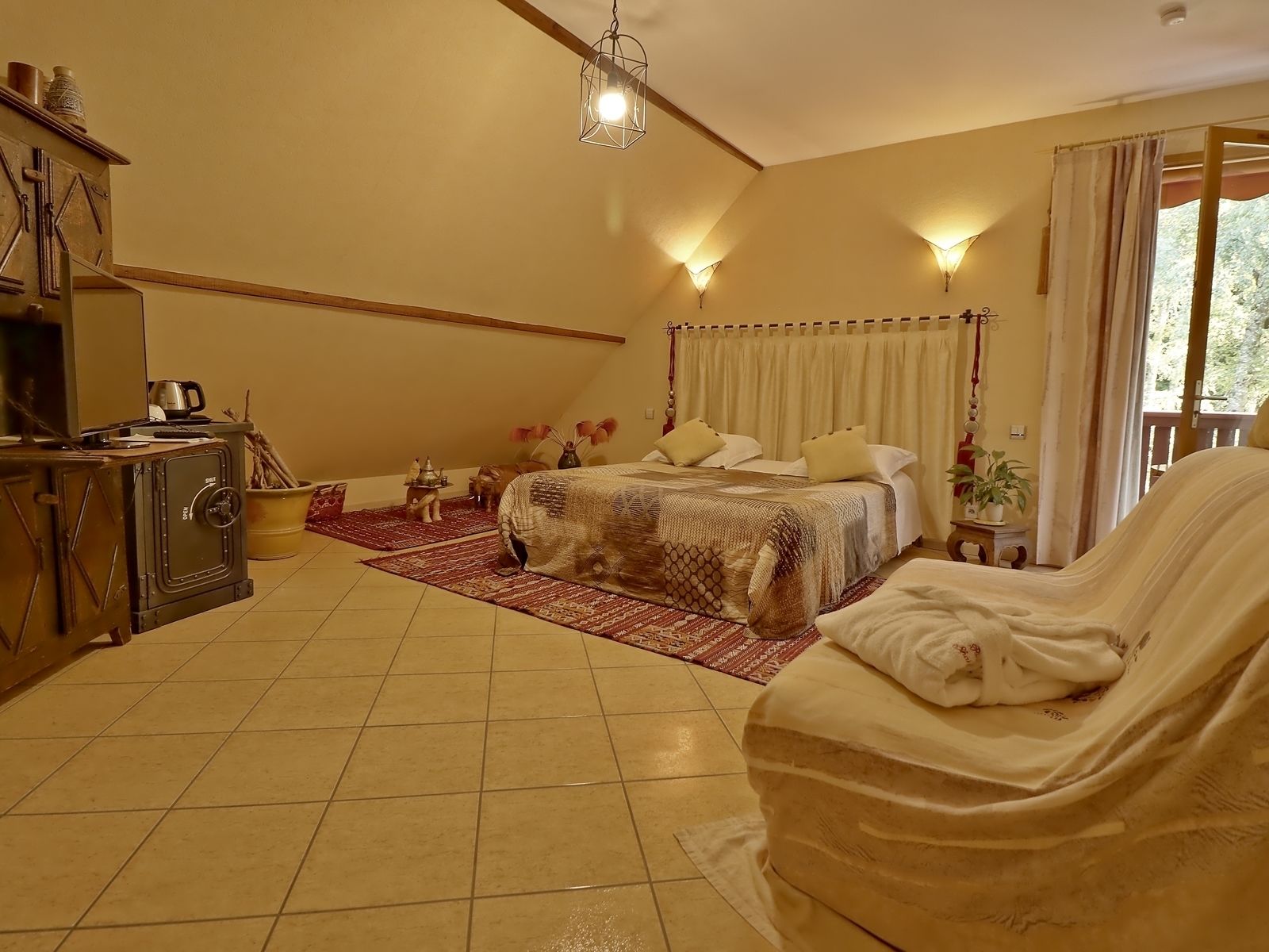 A bedroom with a bed, a sofa, a wooden cabinet, a heater, and a window with curtains.