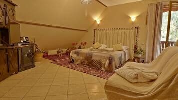A bedroom with a bed, a sofa, a wooden cabinet, a heater, and a window with curtains.