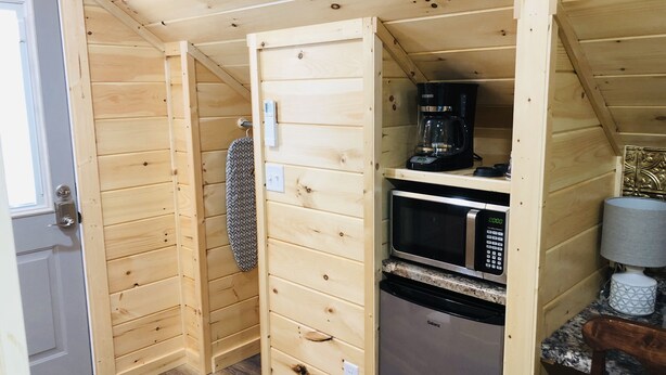 Une cuisine compacte avec des murs en bois, un four à micro-ondes, une machine à café et un petit réfrigérateur.