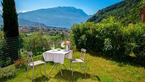 A table set outdoors with chairs, a view of a town and mountains in the background. - Casa Turchese with Private Garden, Pool and Tennis, Riva del Garda, Italy (Riva del Garda)