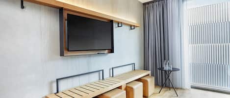 Una sala de estar moderna con televisor empotrado, banca de madera y una mesita baja con vasos.