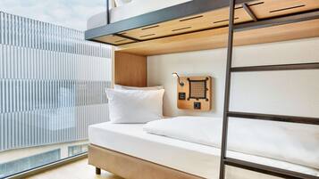 A bunk bed with a wooden ladder, white bedding, and a small wooden shelf with a hook.