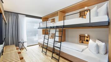 A bunk bed room with a wooden ladder, a small table with bottles, and a window with curtains.
