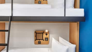 A bunk bed with a wooden headboard, white bedding, and a small table with a lamp.