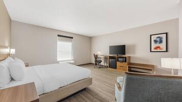 Habitación de hotel con cama, escritorio, televisión y ventana.