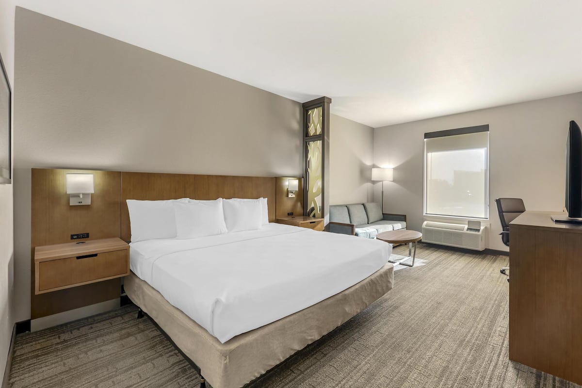 Hotellihuone, jossa on suuri sänky, yöpöydät, työpöytä, tuoli, televisio ja ikkuna.