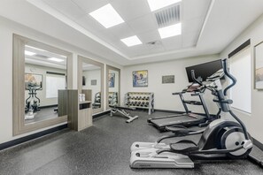 Ein Fitnessraum mit Laufbändern, Crosstrainern und einer Gewichtbank.