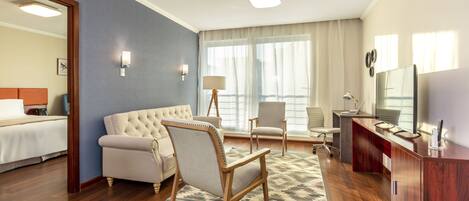 Una habitación de hotel con cama, sofá, escritorio, silla y televisión.