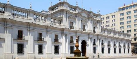 Un edificio histórico con una fuente central y una bandera.
