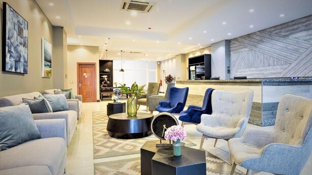 Una sala moderna con un conjunto de sofás, sillones, una mesa de centro y un comedor con mostrador.