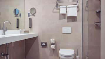 Un baño moderno con lavamanos, espejo, toallero, inodoro y ducha.