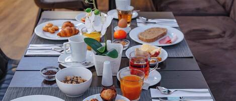 Ein Frühstückstisch mit verschiedenen Speisen, darunter Eier, Gebäck und Saft.
