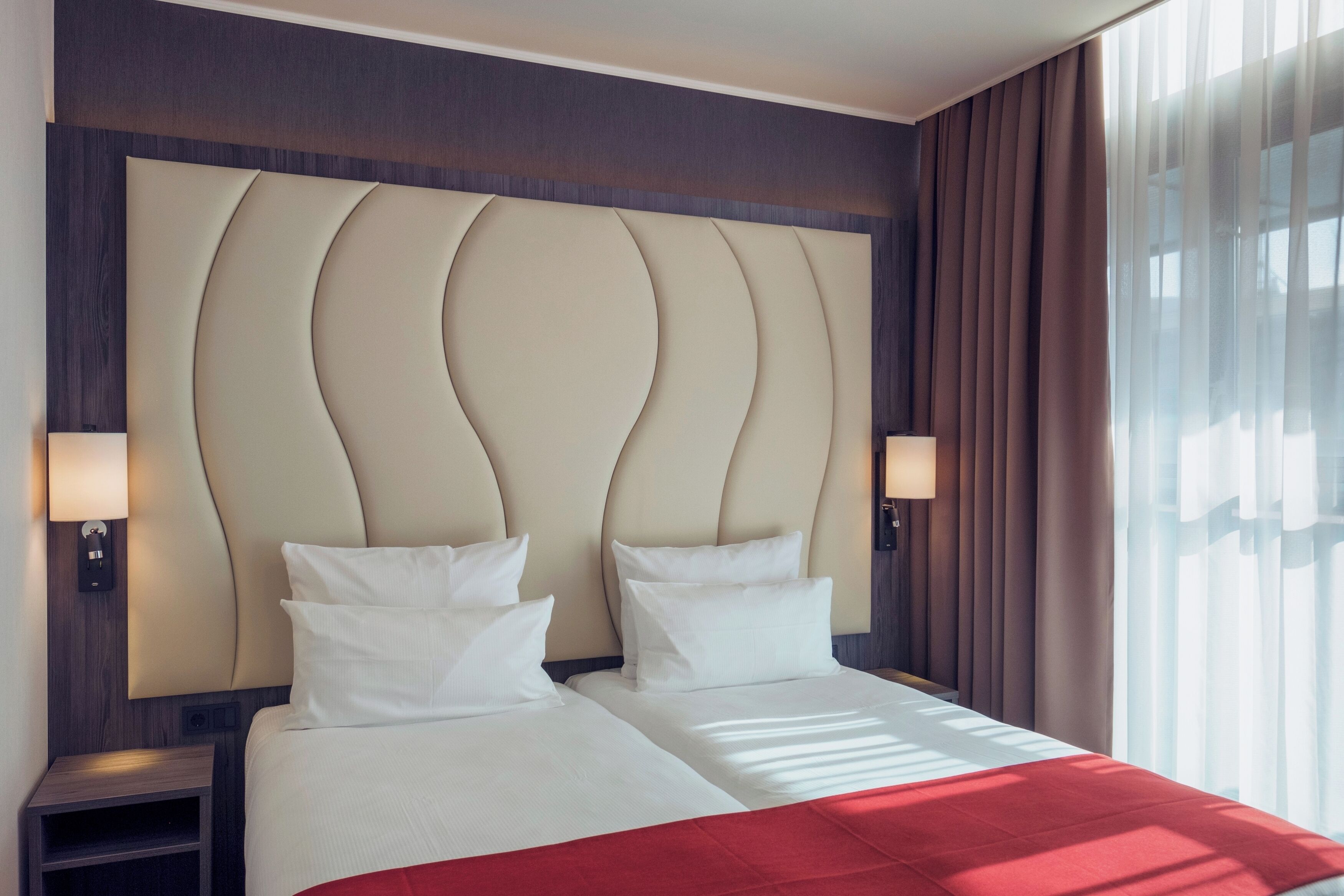 A hotel room with a large bed, two bedside tables, and a headboard with a unique design.