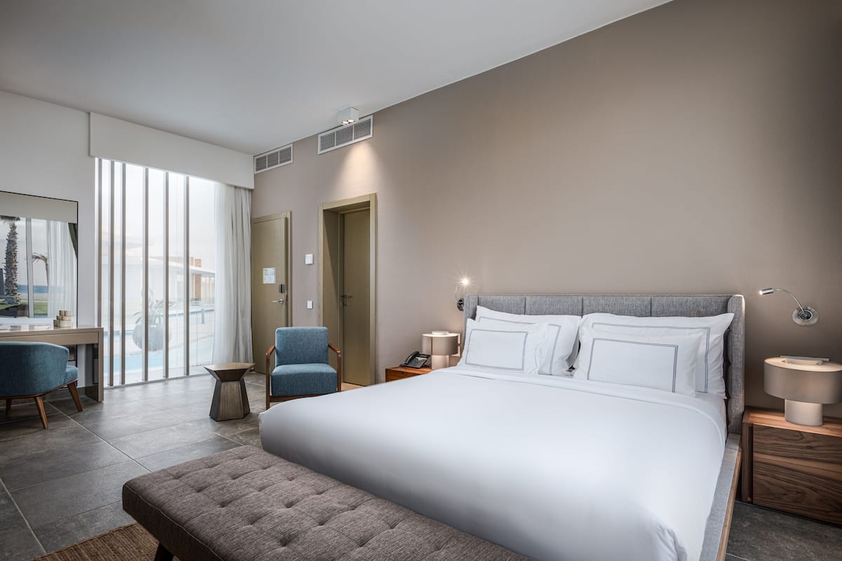 A modern hotel room with a large bed, a desk, and a chair.