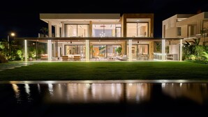 A modern two-story house with a spacious outdoor area, large windows, and a well-lit interior. - The G Hotel Seashell (El Alamein)
