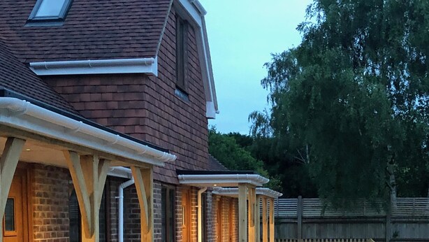A pathway leading to a row of brick buildings with covered porches and a wooden fence in the background.