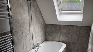 A modern bathroom with a freestanding bathtub, a towel rack, and a skylight.