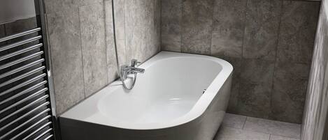 A modern bathroom with a freestanding bathtub, a towel rack, and a skylight.