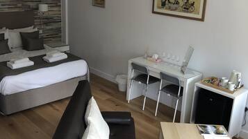A modern hotel room with a bed, a sofa, a desk, and a dining table.