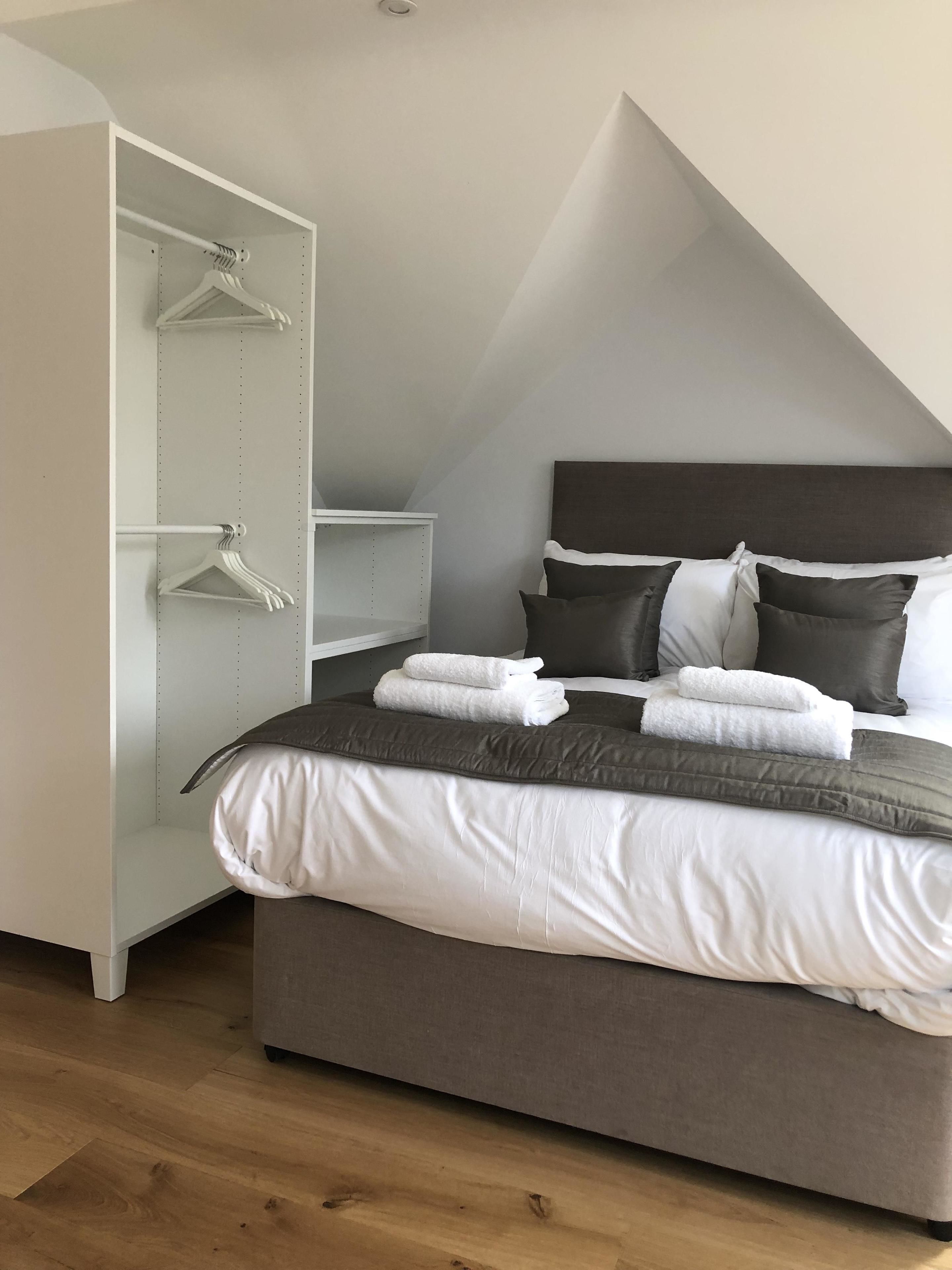 A bedroom with a bed, a wardrobe, and a sloped ceiling.