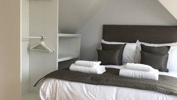 Un dormitorio con cama, armario y techo inclinado.