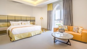 Moderni hotellihuone, jossa on suuri sänky, sohva, sohvapöytä ja näkymä kaupunkiin.