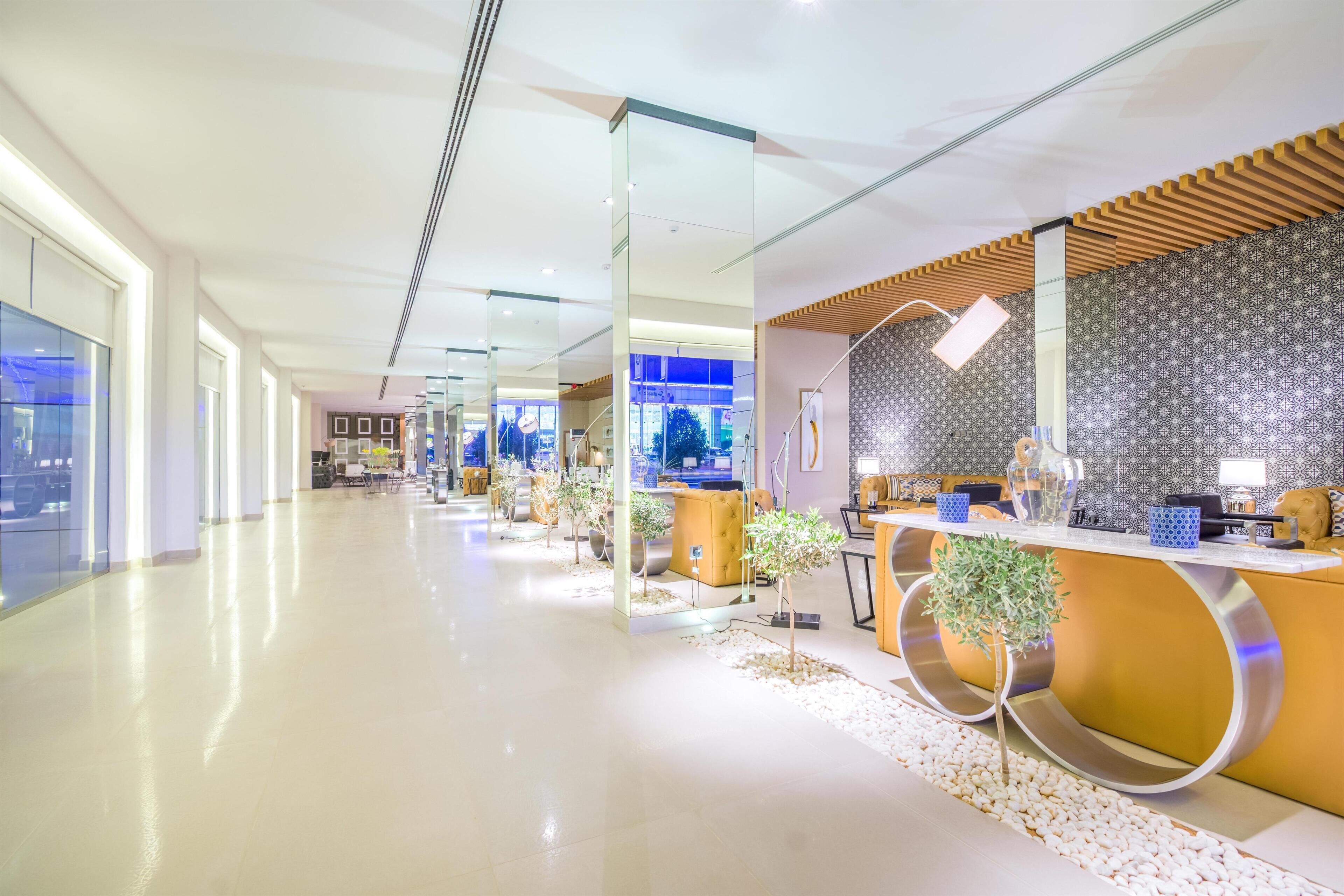 Un área de recepción moderna con un mostrador curvo, separadores de vidrio y plantas en macetas.