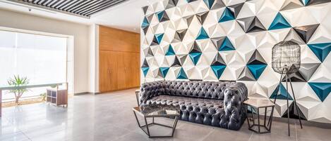 Un interior moderno con una pared de estampado geométrico, un sofá de cuero y una mesa de centro de vidrio.