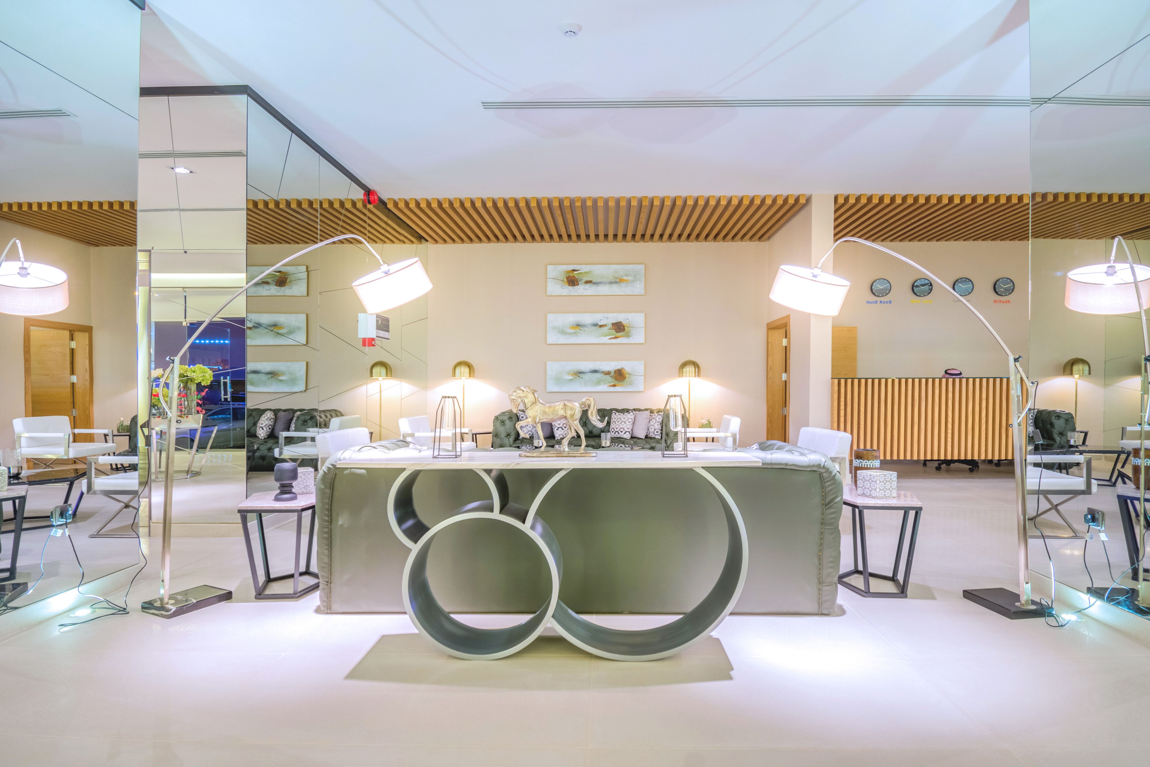 A modern reception area with a central desk, two side tables, and a large decorative sculpture.