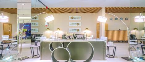 A modern reception area with a central desk, two side tables, and a large decorative sculpture.