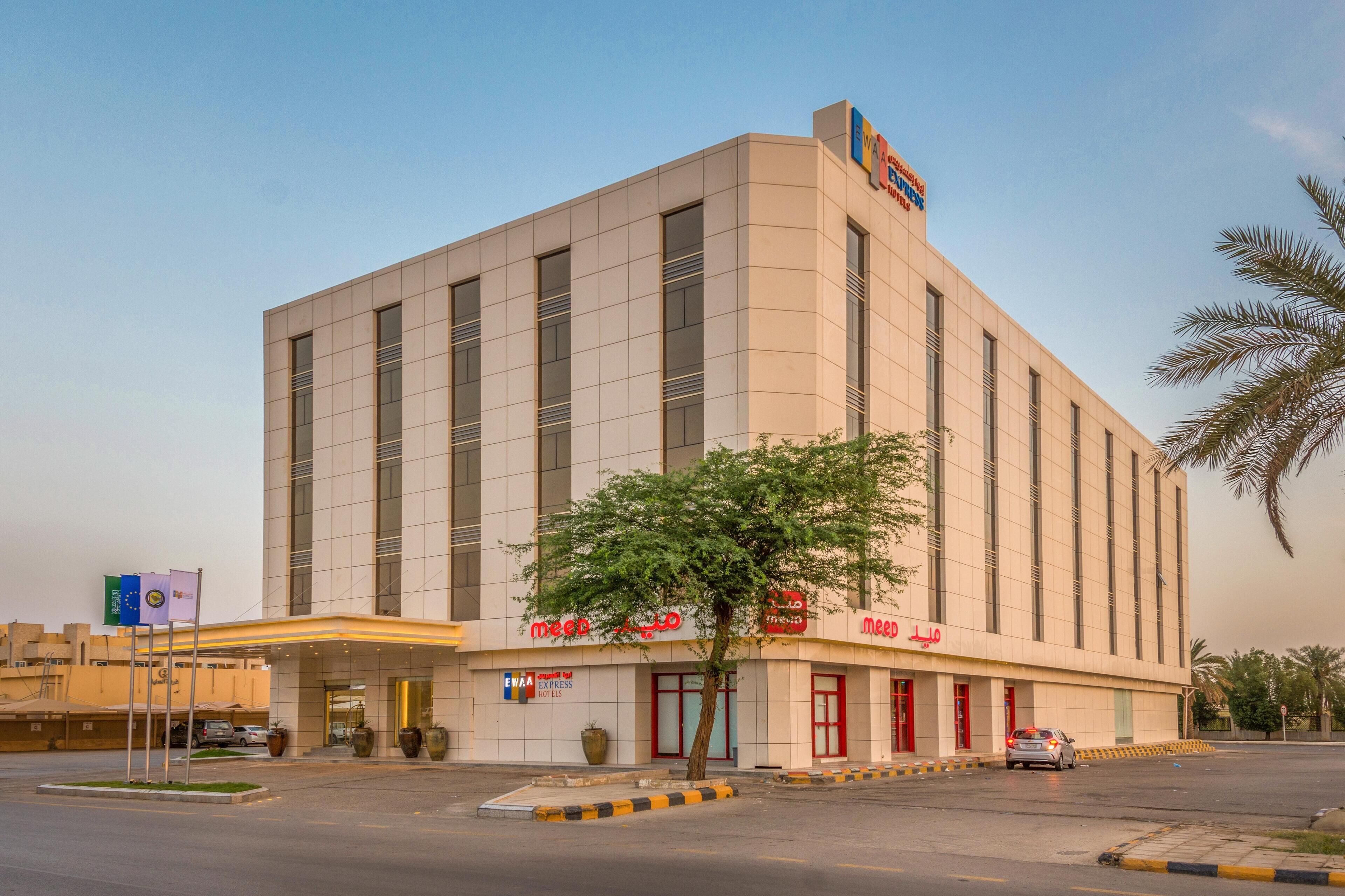 A modern hotel with a prominent entrance, multiple windows, and a sign indicating it is part of the MEED chain.