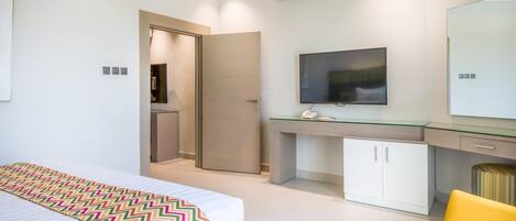 Quarto de hotel moderno com cama, escrivaninha, televisão e guarda-roupa.