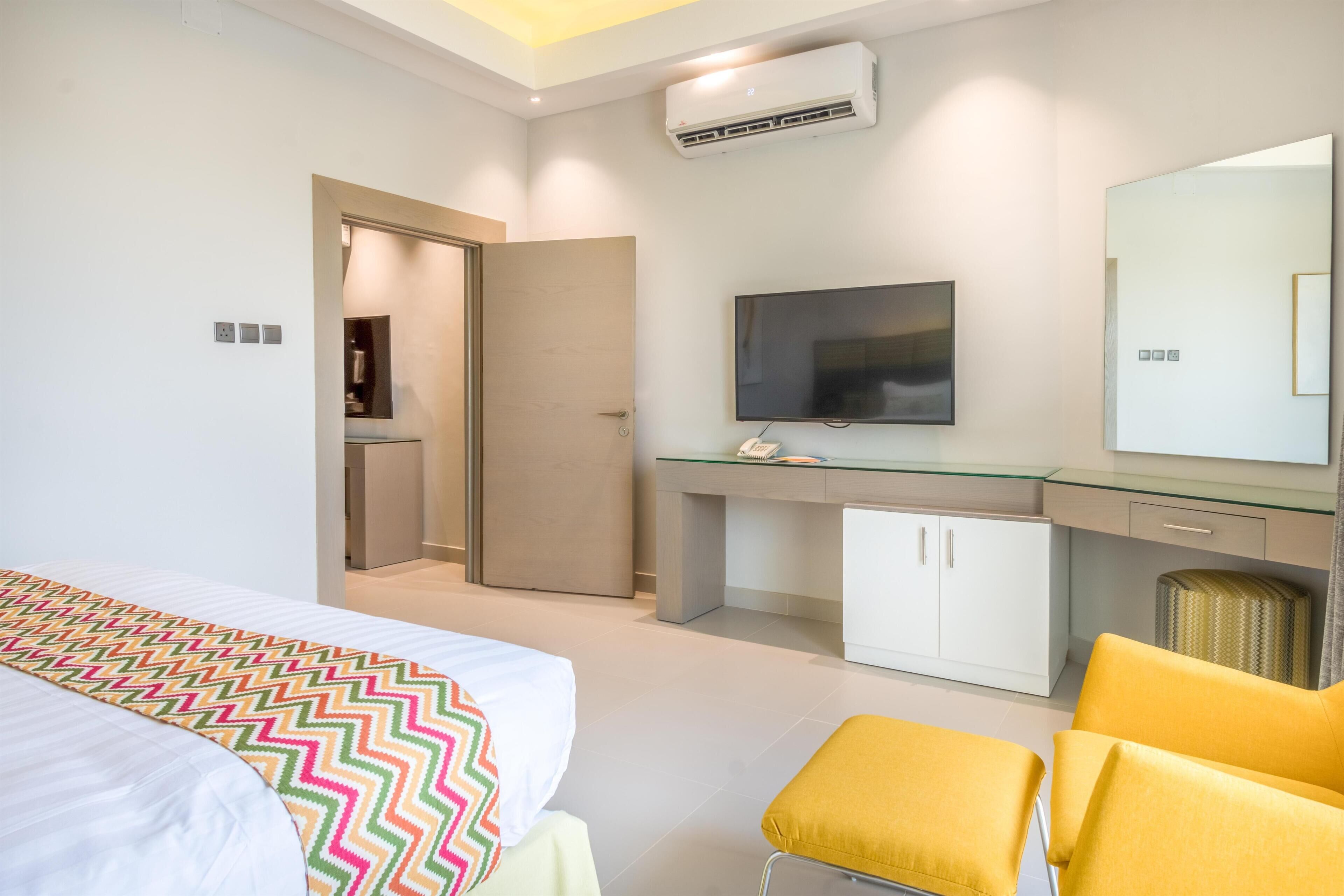 A hotel room with a bed, a TV, a desk, and a mirror.