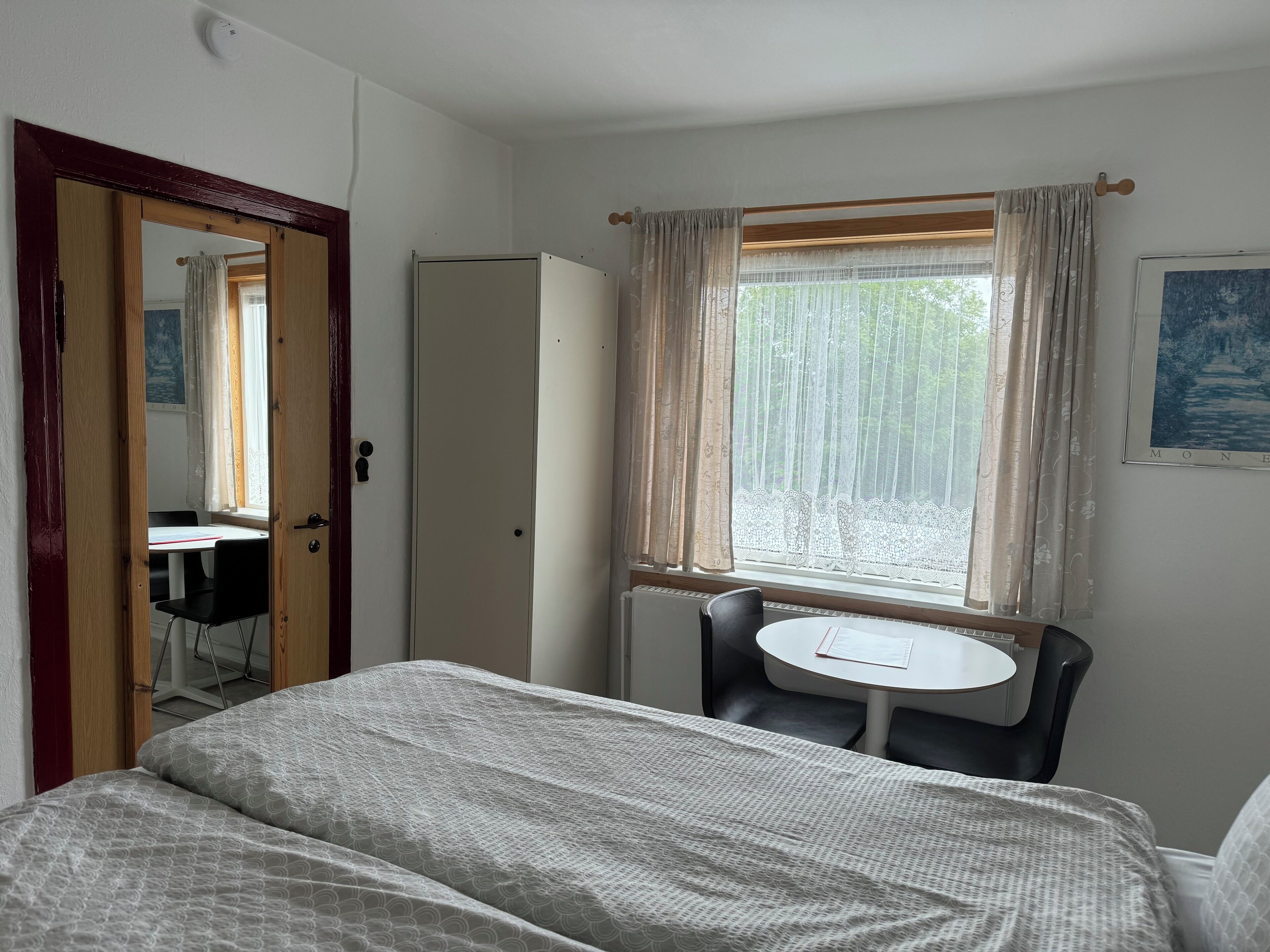A room with a bed, a desk, a chair, a wardrobe, and a window with curtains.