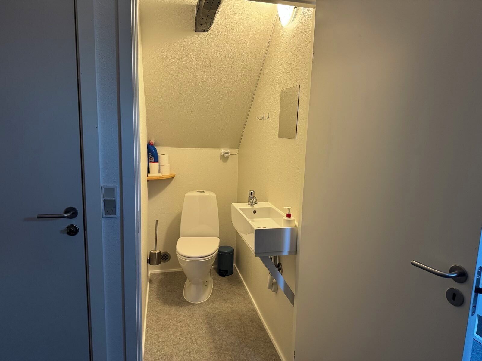 A small, compact bathroom with a toilet, sink, and mirror.