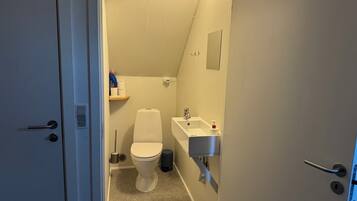 A small, compact bathroom with a toilet, sink, and mirror.