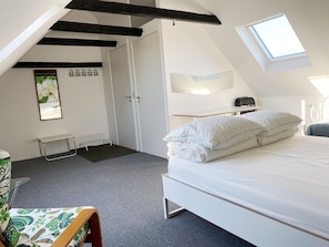 Um quarto com cama, escrivaninha, cadeira, janela e porta.