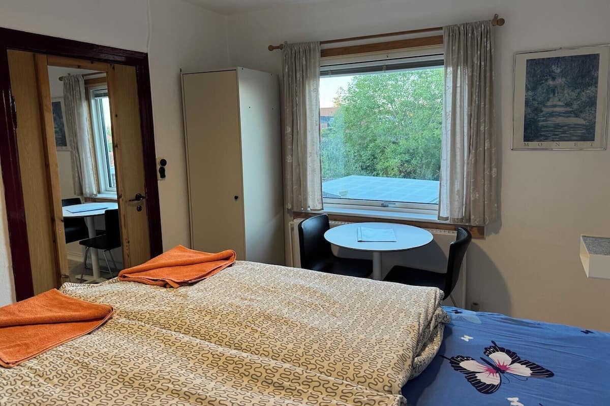 A hotel room with a bed, a desk, and a window with curtains.