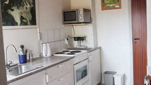 A compact kitchen with a stove, microwave, sink, and a coffee maker.