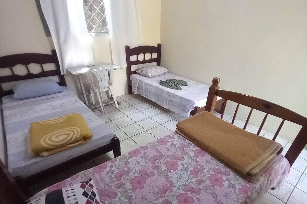 A room with two single beds, a small table, and a window with curtains.